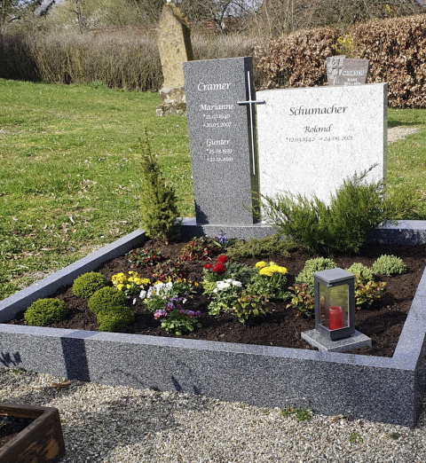 Zwei verschiedene Grabsteine mit Metallkreuz