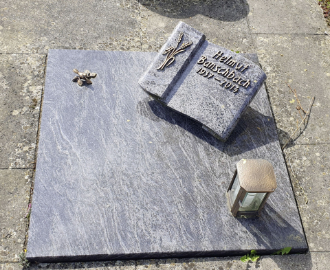 Schlichter Liegestein mit Metallinschrift auf einem abgedeckten Urnengrab