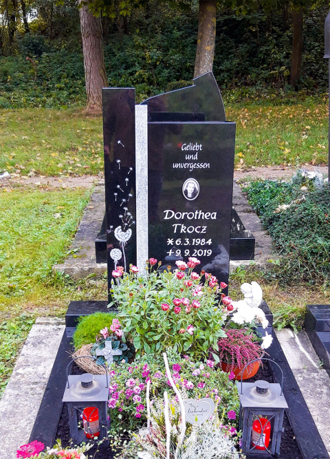 Einzelgrabstein mit dekorativen Elementen auf dem Friedhof