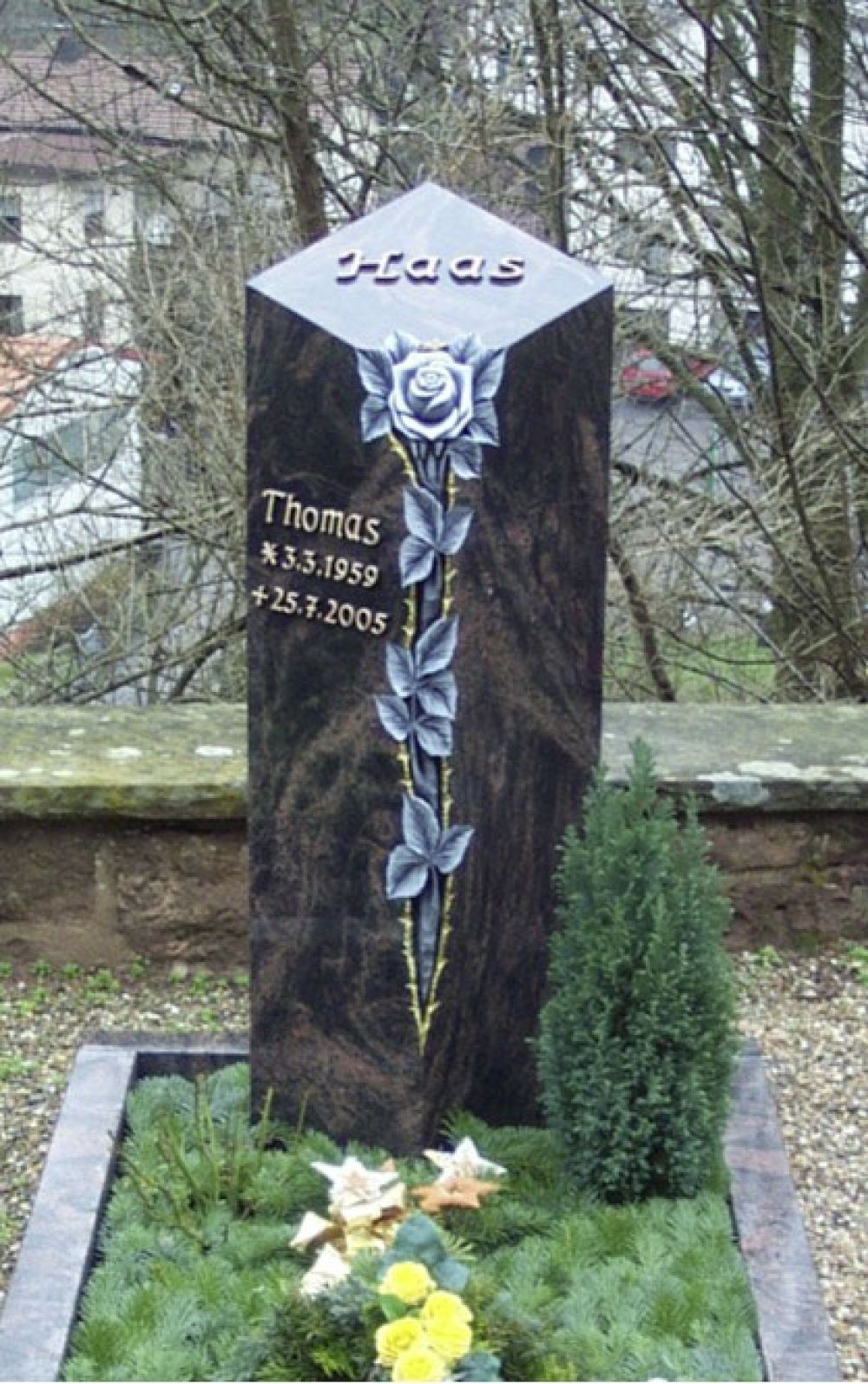Hoher Grabstein mit eingearbeiteten Blumen