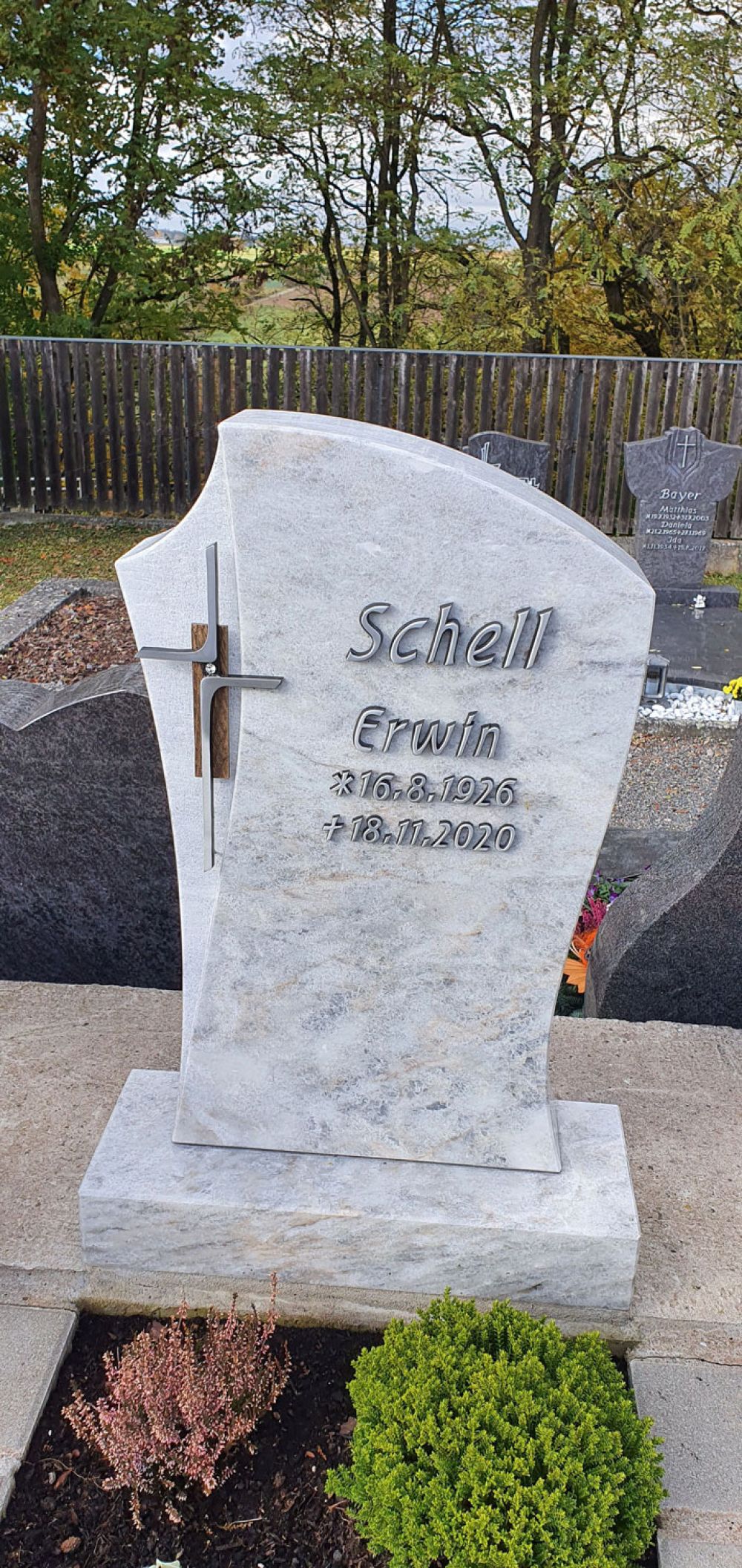 Heller Urnengrabstein mit Metallkreuz
